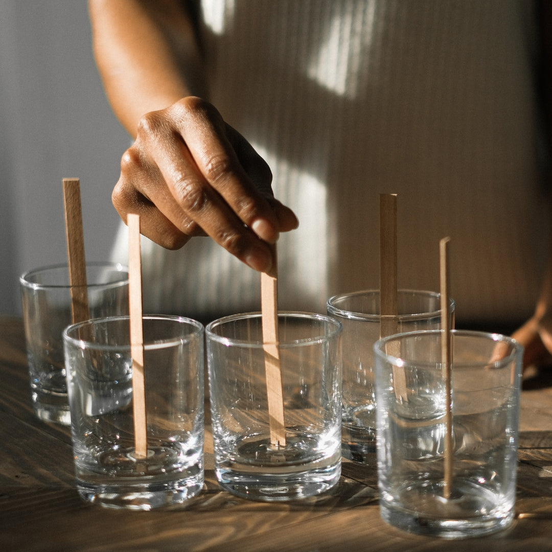 Mèches en bois placées dans des pots en verre avant le coulage de la cire